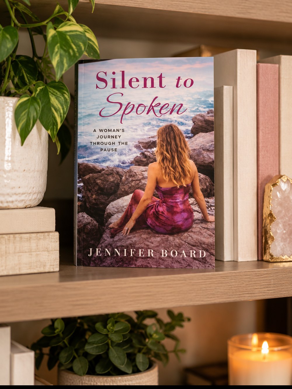Silent to Spoken by Jennifer Board on a bookshelf beside a candle and plants